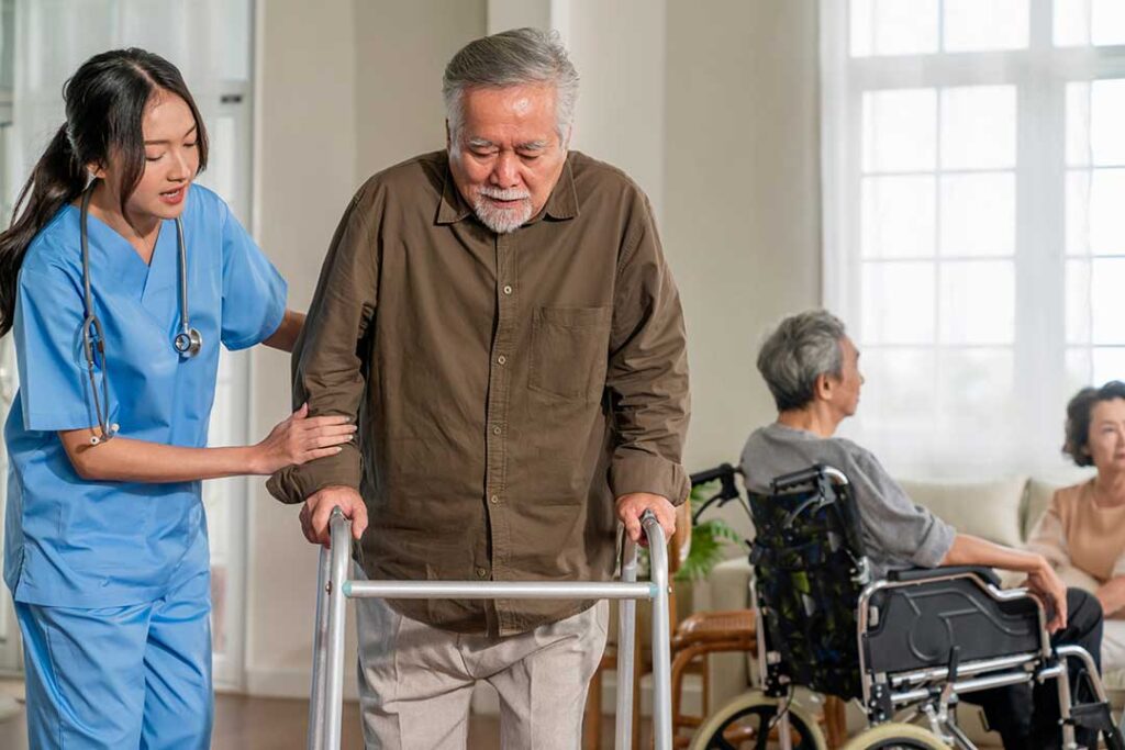 An elderly person unpacks a box of personal belongings in a cozy, sunlit apartment bedroom.